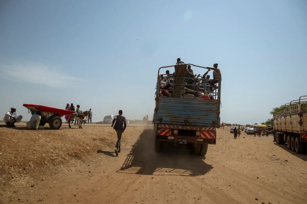 A person chases after a fully loaded truck departing the Joda-Wunthow border point in Renk county, in South Sudan’s Upper Nile state, on Nov. 15 (Rian Cope/AFP via Getty Images)