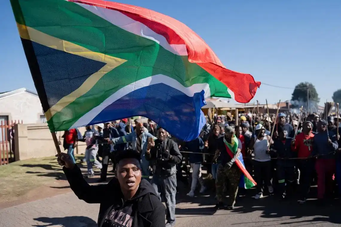 A demonstrator waves South Africa's flag during a protest calling for the deportation of undocumented immigrants, as violence against migrants from other African countries increases, in Benoni, east of Johannesburg, South Africa, June 5, 2026 (REUTERS/Ihsaan Haffejee)