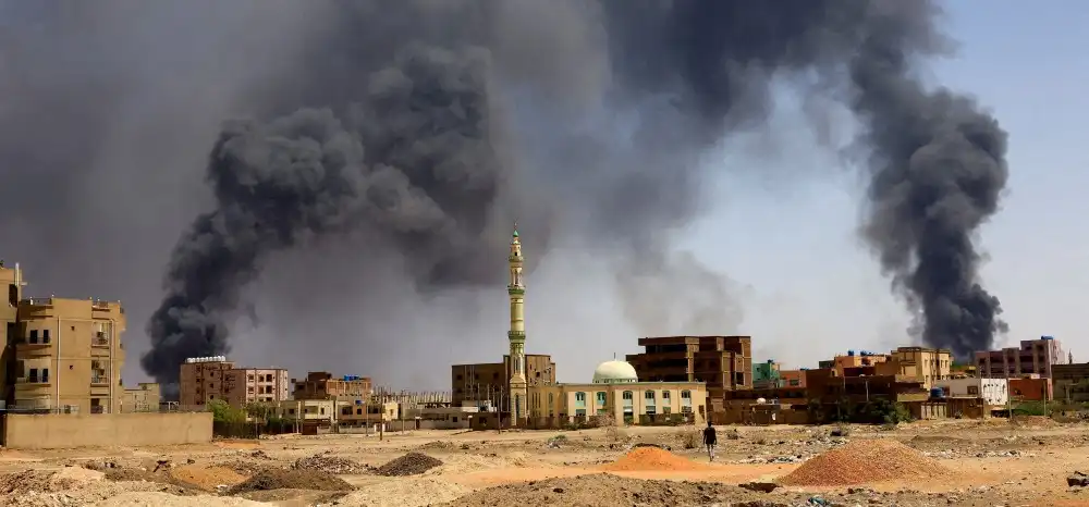 A man walks while smoke rises above buildings after aerial bombardments during clashes between the paramilitary Rapid Support Forces and the army in Khartoum North, Sudan, May 1, 2023. [Photo by REUTERS]