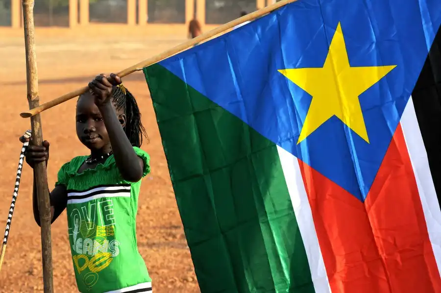 A young girl hangs the South Sudan flag (Timothy McKulka / USAID /  wikipedia)