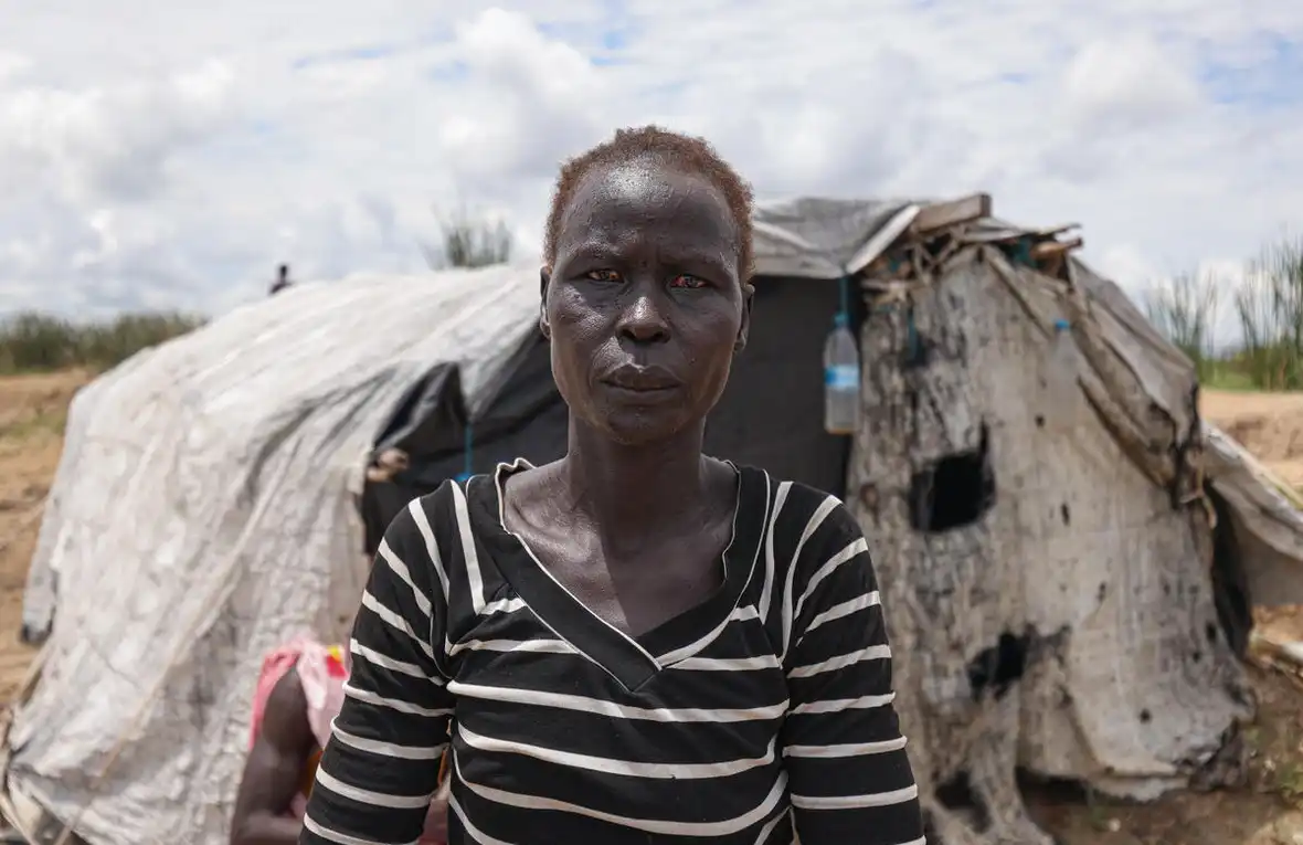 Internally displaced Aduot Wuoi Monjuon poses beside her shelter in Bor, South Sudan, where flooding has displaced her family from their village in Jonglei State (© UNHCR/Tiksa Negeri)