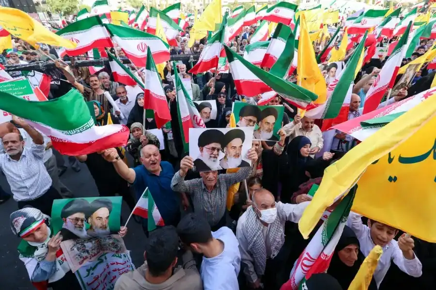 Iranians chant slogans, wave national flags, and hold portraits of Iranian supreme leader Ayatollah Ali Khamenei (L) and late supreme leader Ayatollah Ruhollah Khomeini, as they celebrate a ceasefire between Iran and Israel at Enghlab Square in the capital Tehran on June 24, 2025 (Photo Credit: USA Today)