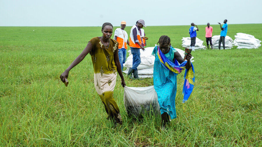 Nyaduoth (L) and a fellow villager drag WFP food assistance away from an airdrop zone (Photo: WFP/Peter Louis)