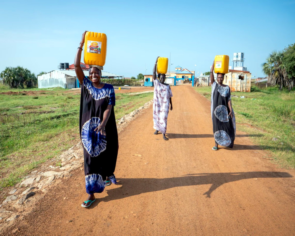 Nyandong Chang (left) and her friends carry water from a water kiosk to their homes in Bor, South Sudan (Florence Miettaux)