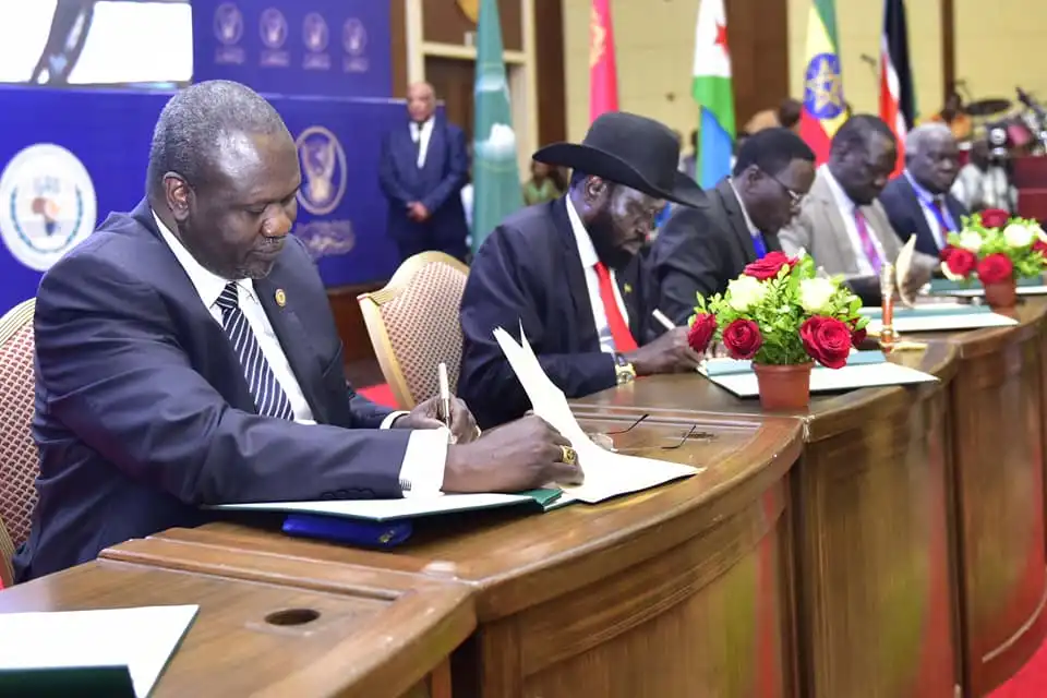South Sudan rebel leader Riek Machar (extreme left) and president Salva Kiir (in hat) signing peace agreement (PPU Photo)
