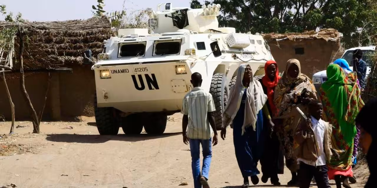 Sudanese refugees walk past a UN vehicle in South Darfur. Sudanese gunmen on December 28, 2021 looted a WFP warehouse containing some 1,900 tonnes of food aid in Darfur (FILE | AFP)