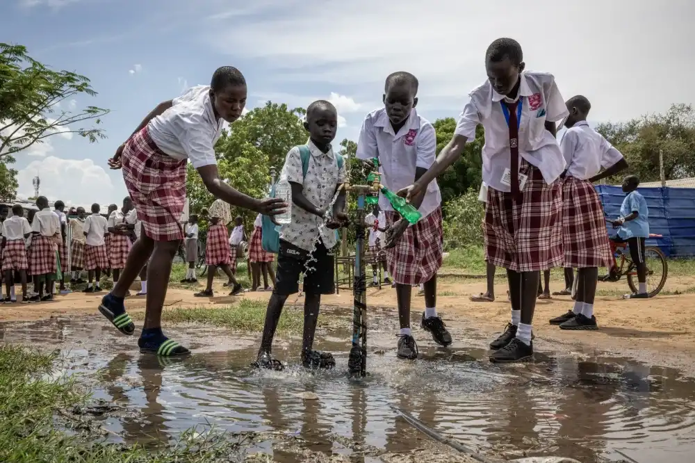 The students filling water bottles from a borehole in the schoolyard (Photograph by Ed Ram)