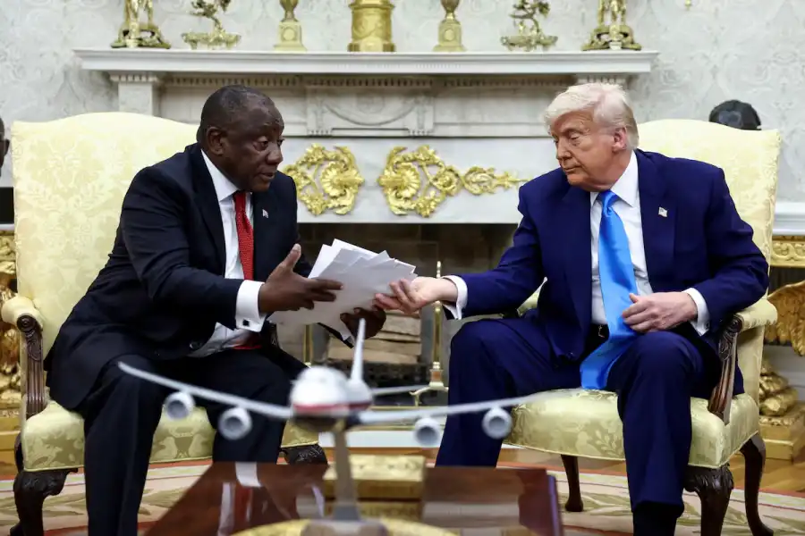 U.S. President Donald Trump hands over to South African President Cyril Ramaphosa copies of articles that he said showed white South Africans who had been killed, in the Oval Office of the White House in Washington, D.C., U.S., May 21, 2025 (REUTERS/Kevin Lamarque)