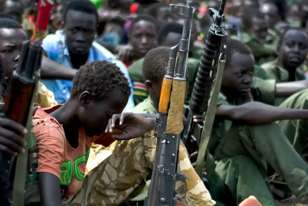 This photo from Feb. 10 shows young boys, child soldiers, sitting with their rifles at a ceremony of disarmament, demobilization and reintegration in Pibor overseen by UNICEF and partners. (Charles Lomodong/AFP/Getty Images)